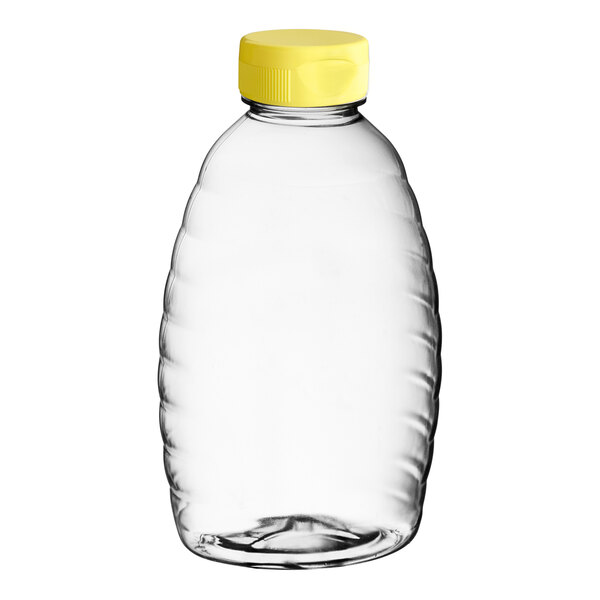 A clear plastic Classic Queenline honey bottle with a yellow flip top lid.