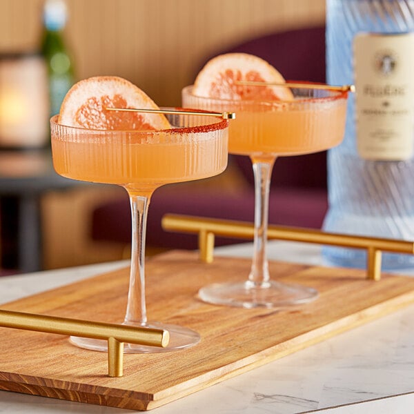 Two glasses of pink Fluere Non-Alcoholic Smoked Agave Mezcal cocktail with orange slices.