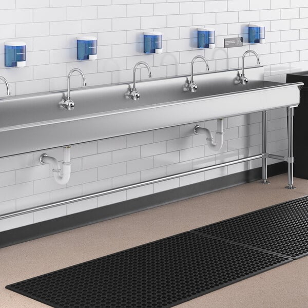 A Waterloo wall mount hand sink with 5 hands-free faucets over a black counter.