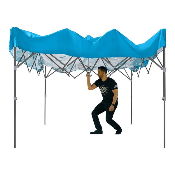 A man in black standing under a blue E-Z Up canopy tent with a gray frame.