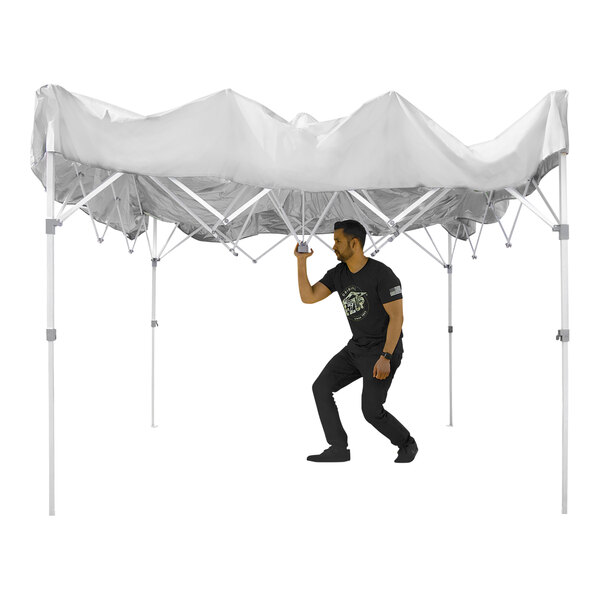 A man in black holding up a white E-Z Up canopy tent.