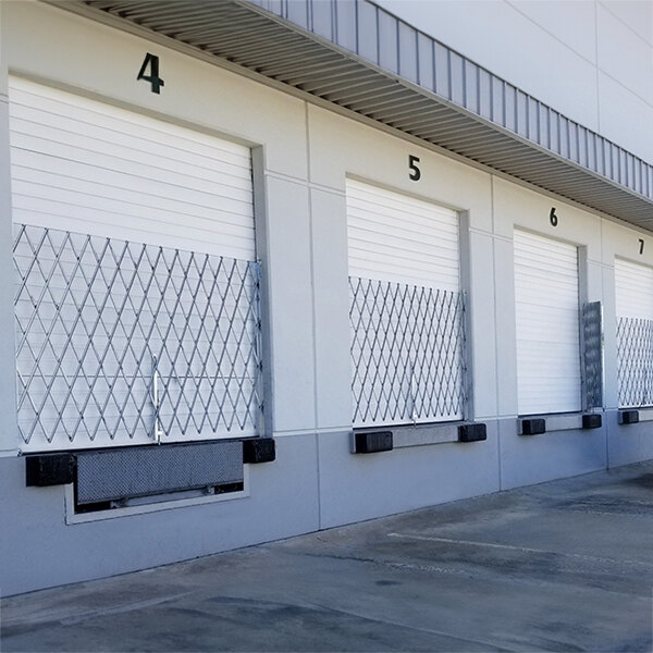 A row of Illinois Engineered Products galvanized steel folding security gates in front of storage units.