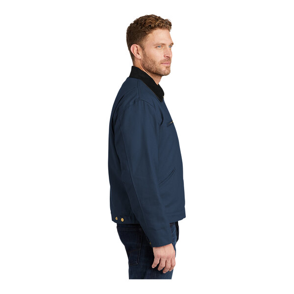 A man wearing a navy CornerStone work jacket with a black corduroy collar.