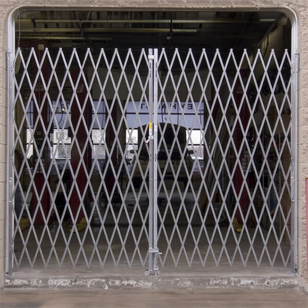 A white metal Illinois Engineered Products heavy-duty folding double security gate with a diamond pattern.