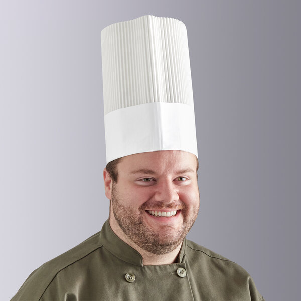 A man wearing a Choice disposable white chef hat smiling.