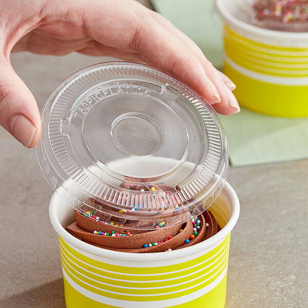 A hand placing a Choice clear plastic lid on a yellow container.