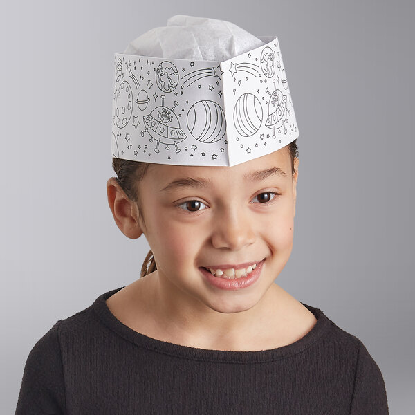 A child wearing a white paper hat with alien drawings.