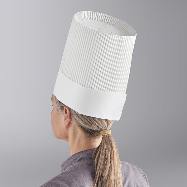 A woman wearing a Choice white disposable chef hat.