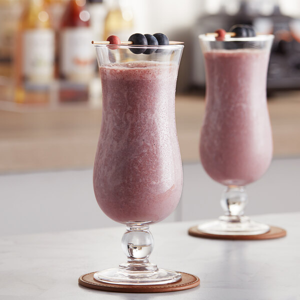 A table with two glasses of pink smoothie topped with blueberries.