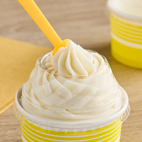 A close up of a yellow Choice plastic lid with a spoon in a cup of frozen yogurt.