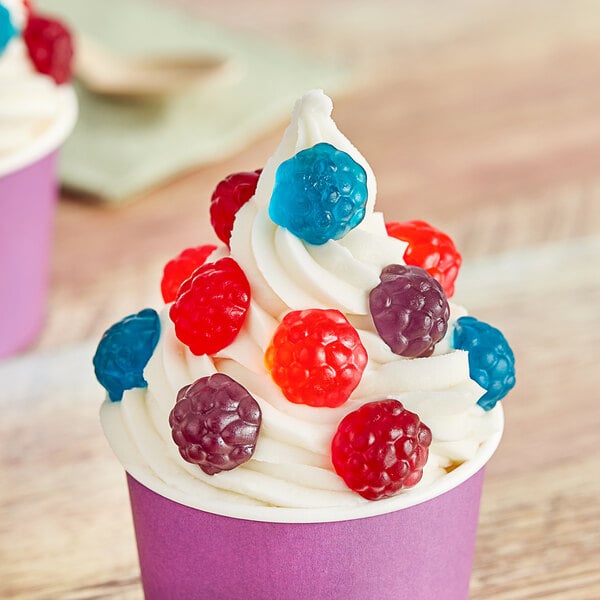 A cupcake with whipped cream and Albanese Mixed Gummi Berries on top.