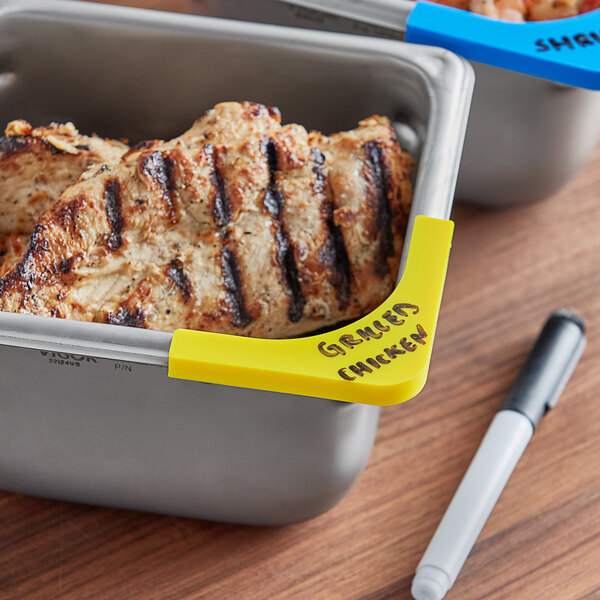 A yellow Vigor corner label for a food pan with a pen.