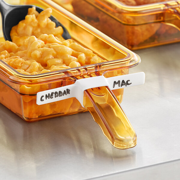 A plastic Vigor high-heat food pan label in a container of macaroni and cheese with a spoon.