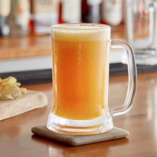 A glass of mango puree on a table with a coaster.