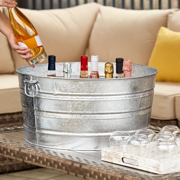 A person pouring wine from a bottle into a Behrens steel tub on an outdoor patio.