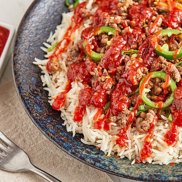 A plate of rice and meat with Underwood Ranches Sambal Chili Hot Sauce.