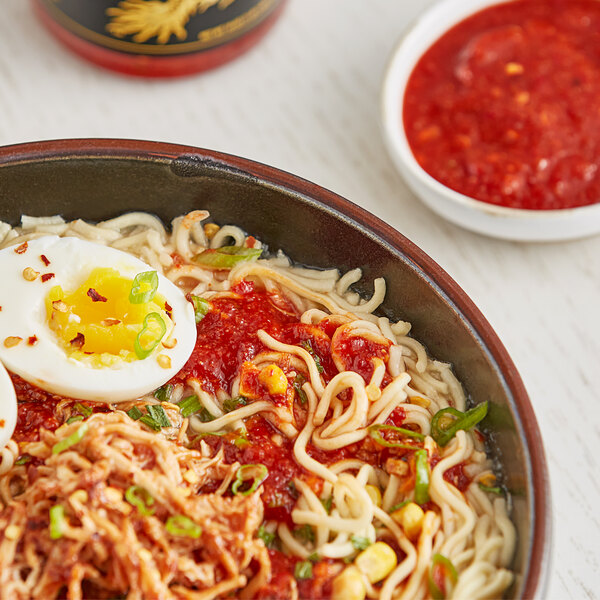 A bowl of noodles with Underwood Ranches Premium Chili Garlic Hot Sauce and a boiled egg.