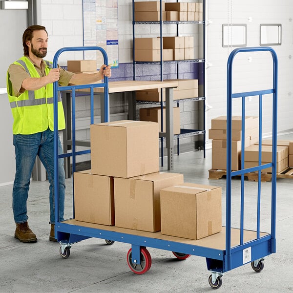 A man pushing a Lavex blue heavy-duty wood utility cart with stacked boxes on it.