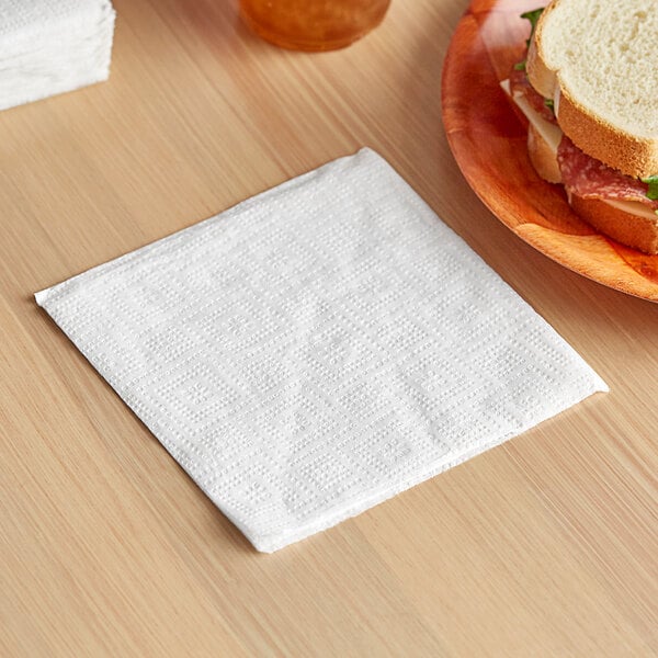 A Seventh Generation luncheon napkin on a table with a sandwich and a drink.