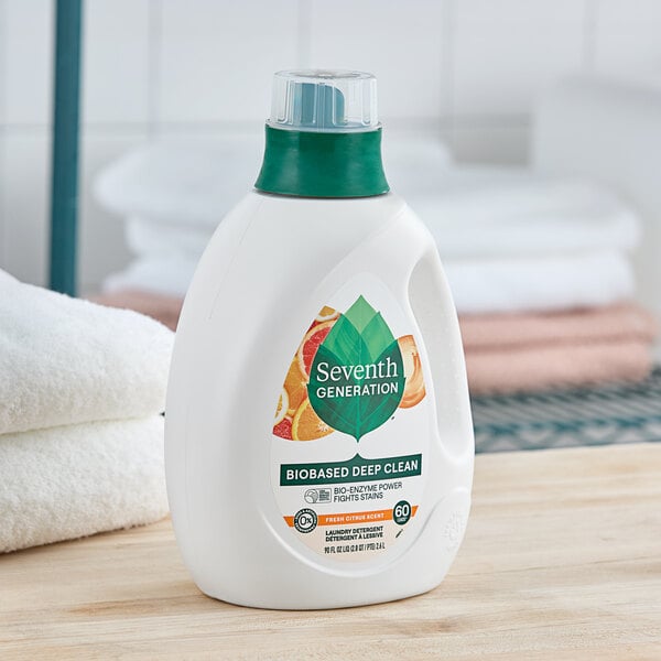 A white bottle of Seventh Generation Citrus Liquid Laundry Detergent with a green cap and label on a table.