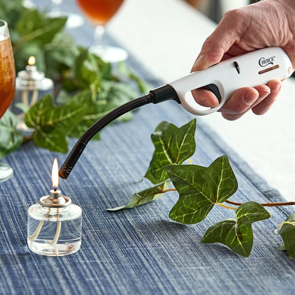 A hand holding a Choice Multi-Purpose Lighter with a flexible nozzle over a lit candle.