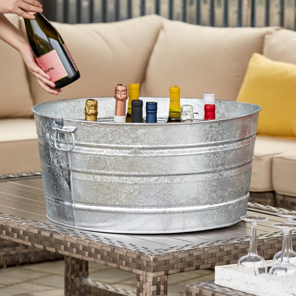 A person using a Behrens metal tub as a wine cooler on an outdoor patio table.