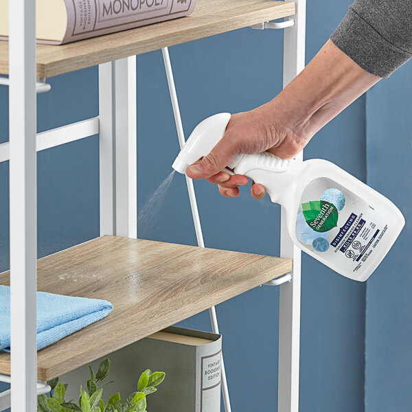 A person spraying a Seventh Generation hydrogen peroxide disinfecting spray bottle on a shelf.