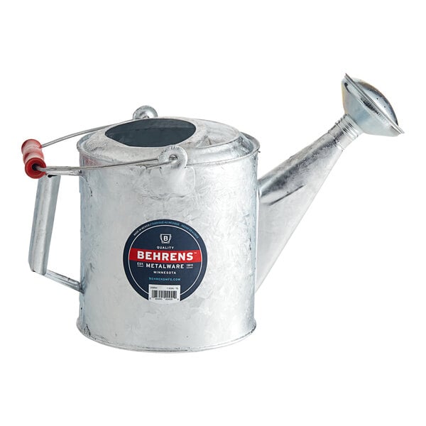 A silver Behrens steel watering can with a red handle.