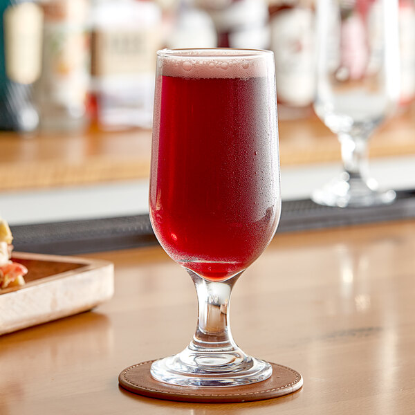 A glass of Endless Harvest raspberry fruit puree on a table with a coaster.