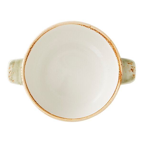 A round, white soup bowl with a rustic brown rim and two green handles.