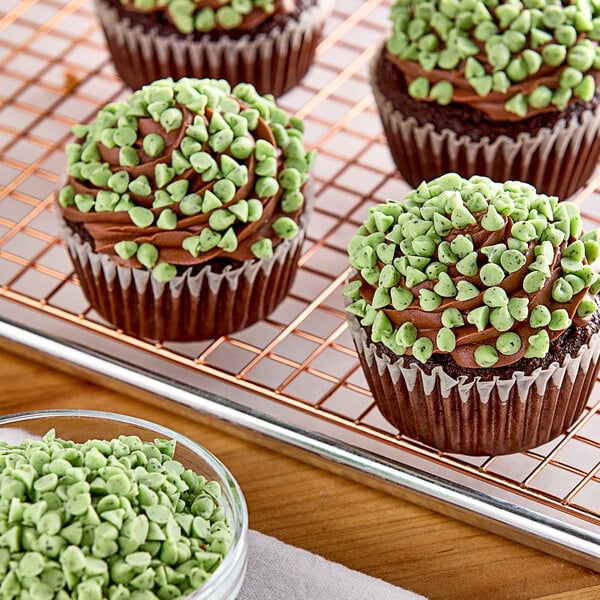 A group of chocolate cupcakes with green mint chips on top.