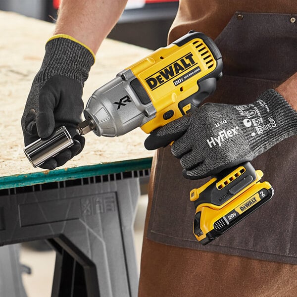 A person using a yellow and black DeWalt cordless impact wrench.