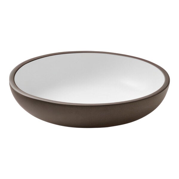 A close up of a white Playground ReNew deep coupe plate with a brown rim.