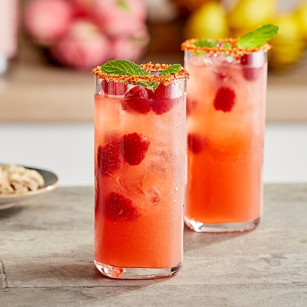 Two glasses of Torani raspberry puree with berries on the rim.