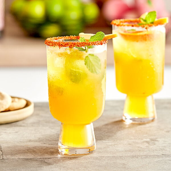 Two glasses of yellow Torani peach drinks with mint leaves.