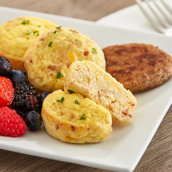 Abbottsford Farms Fully Cooked Cage-Free Bacon and Cheese Egg Bites on a plate with fruit.