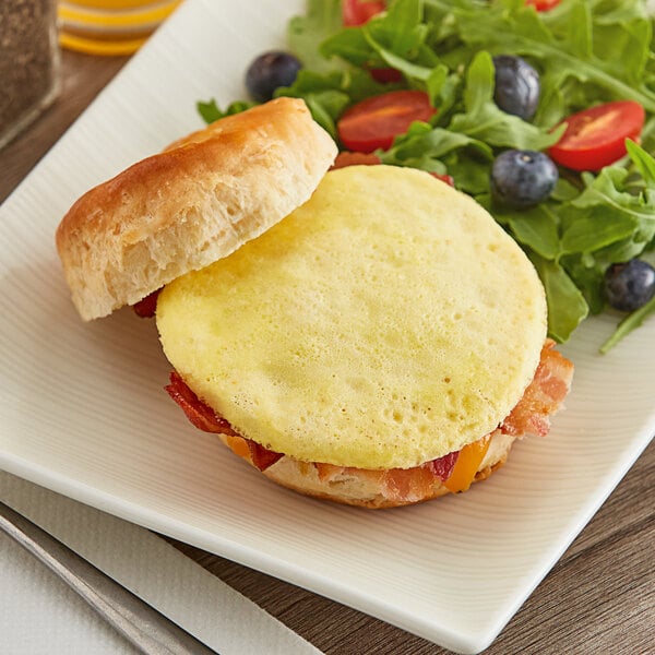 A breakfast sandwich with Papetti's scrambled egg patty, bacon, and cheese on a white surface.