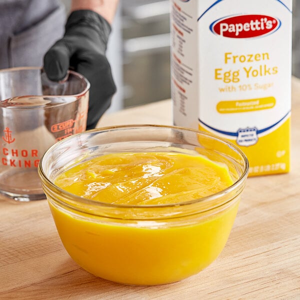 A person mixing Papetti's frozen liquid sugared egg yolks in a glass bowl.