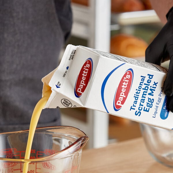 A person pouring milk into a glass bowl.