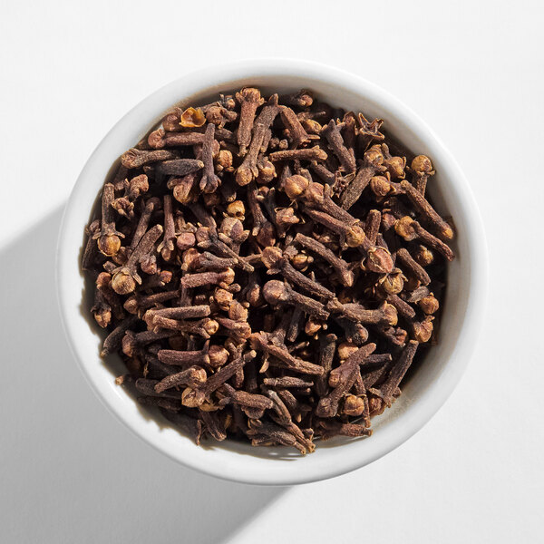 A white bowl filled with whole cloves.