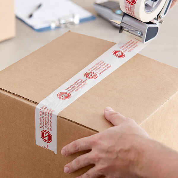 A person's hand using Tape Logic "Stop / Alto" tape to seal a box.