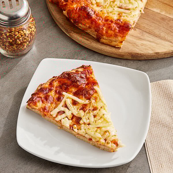 A slice of pizza on a plate with red pepper flakes.