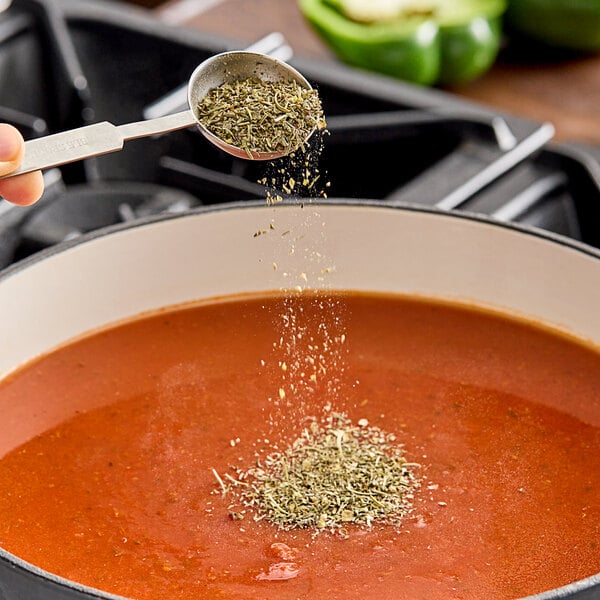 A person sprinkling Hometown Provisions Italian Seasoning into a pot of soup.