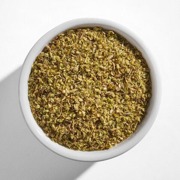 A white bowl filled with dried oregano leaves.