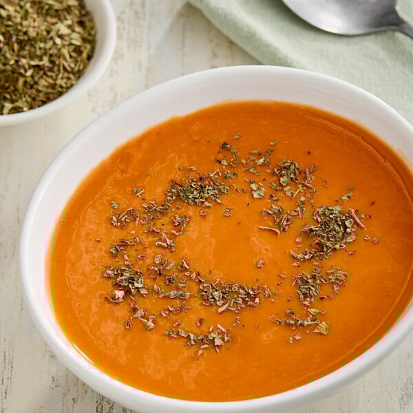 A bowl of soup with dried basil leaves on top.