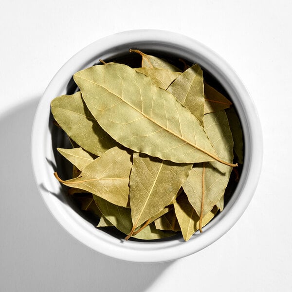 A white bowl filled with dried bay leaves.