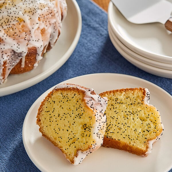 A piece of poppy seed cake with white frosting and black specks on a plate.