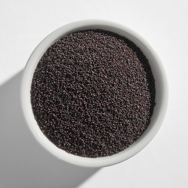 A white bowl filled with black poppy seeds.