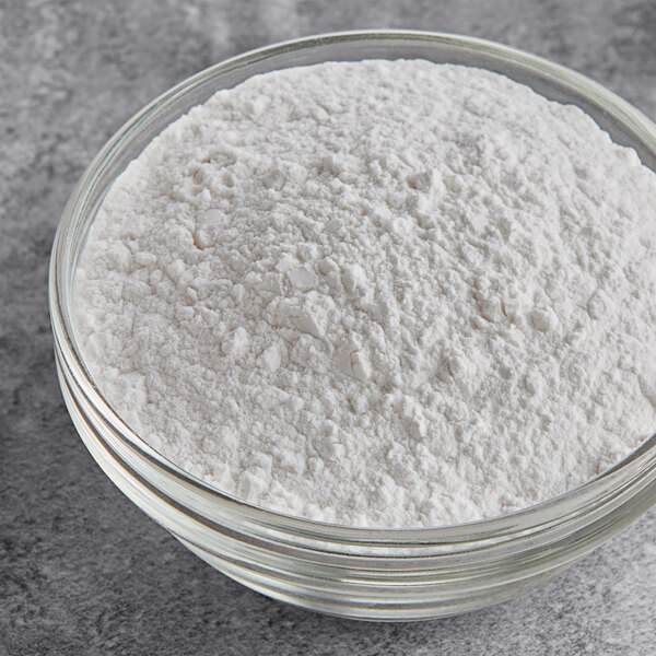 A glass bowl filled with white cream of tartar powder.