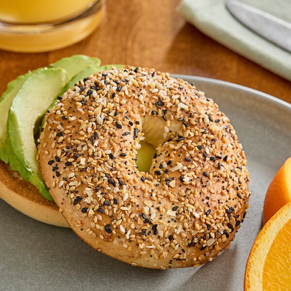 A bagel topped with Hometown Provisions Everything Bagel Seasoning with avocado and orange slices on a plate.